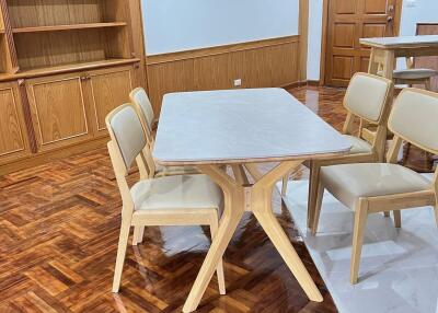 Dining area with table and chairs, wooden flooring and built-in bookshelves