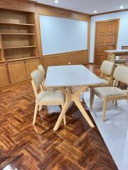 Dining area with table and chairs, wooden flooring and built-in bookshelves