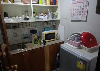 Small, compact kitchen with open shelves and basic appliances