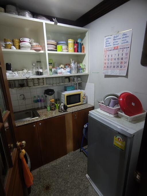 Small, compact kitchen with open shelves and basic appliances