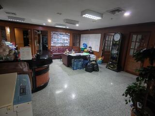 Building lobby with seating area, reception desk, and large clock