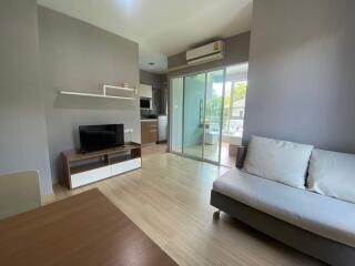 Modern living room with TV, air conditioning, and large sliding glass doors leading to a balcony