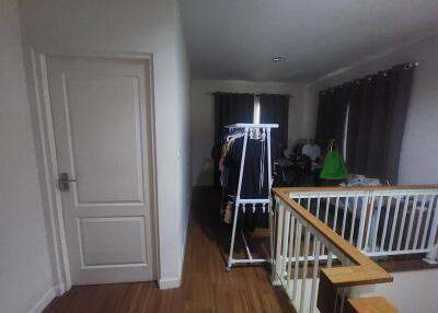 Brightly lit bedroom with clothes rack and wooden flooring