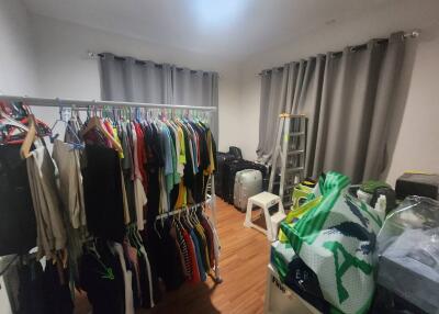 Bedroom with clothes rack, suitcases, step stool, and cardboard boxes