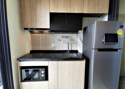 Modern kitchen with stainless steel refrigerator, electric stove, microwave, and wooden cabinets