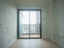 View of an empty room leading to a balcony through glass sliding doors