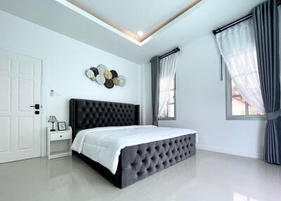 Modern bedroom with large windows and a tufted bed