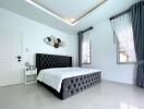 Modern bedroom with large windows and a tufted bed