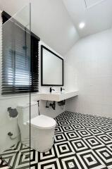 Modern bathroom with geometric floor tiles and glass shower partition