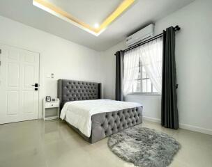 Modern bedroom with gray padded bed and white bedding