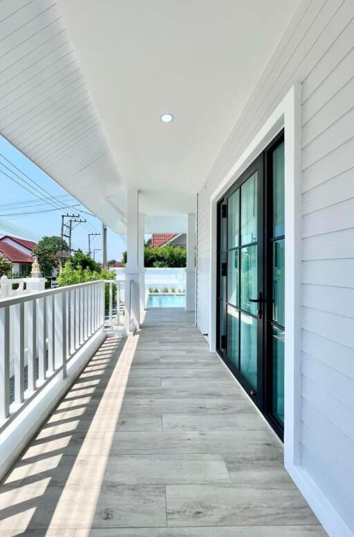 A view of a spacious balcony with wooden flooring and elegant railing