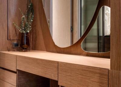 Modern bedroom vanity area with wooden drawers and unique mirror design