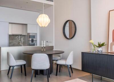 Modern dining area with round table, chairs, and kitchen in background