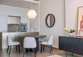 Modern dining area with round table, chairs, and kitchen in background