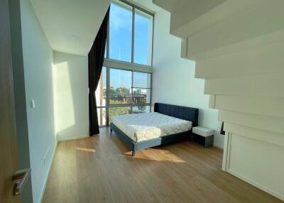 A modern bedroom with a high ceiling and large window