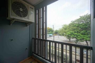 Balcony with air conditioning unit and view of trees and street