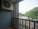 Balcony with air conditioning unit and view of trees and street