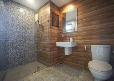 Modern bathroom with wooden paneling and tiled shower area