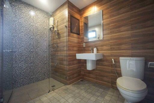 Modern bathroom with wooden paneling and tiled shower area