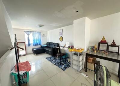 Well-lit living room with black sofa and small workspace