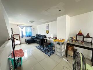 Well-lit living room with black sofa and small workspace