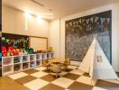 Children's playroom with chalkboard, cubby storage, teepee, and small table with chairs