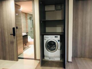 Laundry area with a washing machine and a view into the bathroom