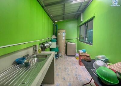 Green-walled kitchen with sink, water heater, and various kitchen items