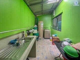 Green-walled kitchen with sink, water heater, and various kitchen items