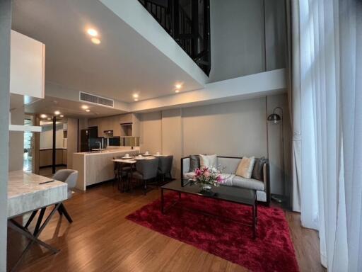 Modern living room with high ceiling, hardwood floor, and contemporary furniture