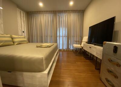 Modern and stylish bedroom with wooden flooring, a large bed, and a flat-screen TV