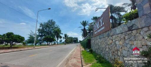 Roadside with a stone wall, trees, and a sign of a location