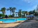 Outdoor pool area with seating and palm trees