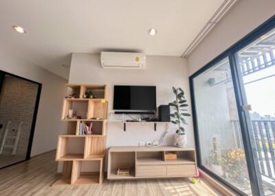 Living room with wooden floor, shelving units, TV on wall, air conditioner, and sliding glass door