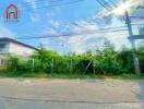 Street view of vacant lot with surrounding greenery