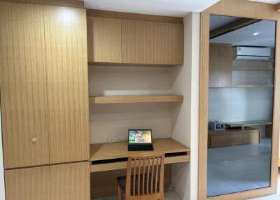 Wooden home office with desk, chair, shelves, and closet