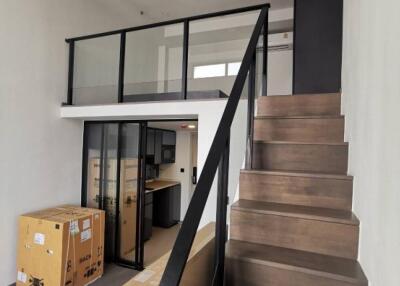 Modern loft-style living area with a staircase and glass balcony