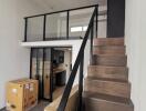 Modern loft-style living area with a staircase and glass balcony