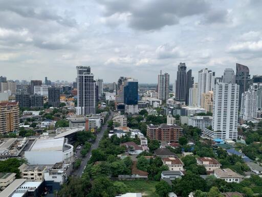 Aerial view of urban skyline with high-rise buildings and lush greenery.