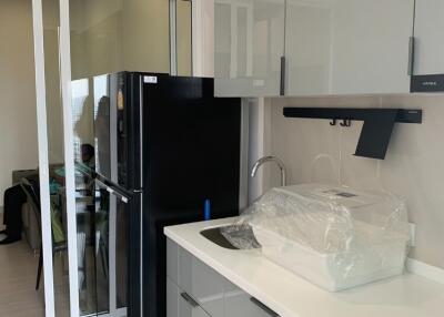 Modern kitchen with sleek cabinets, black fridge, and sliding door
