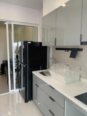 Modern kitchen with sleek cabinets, black fridge, and sliding door