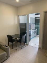 Small living area with a glass table and two chairs, adjacent to a modern kitchen