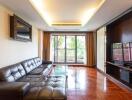 Modern living room with leather sofas, TV, and large windows