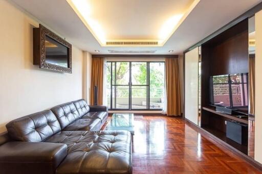 Modern living room with leather sofas, TV, and large windows