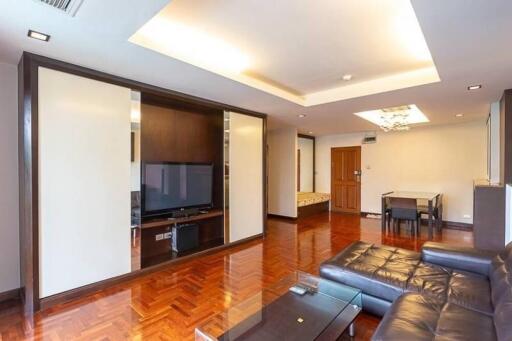 Modern living room with wooden flooring, recessed ceiling lights, and a large TV