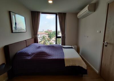 Cozy bedroom with a large window and modern furnishing, including air conditioning.