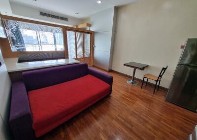 Living room with a red and purple sofa, wooden floor, and large windows.