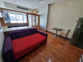 Living room with a red and purple sofa, wooden floor, and large windows.