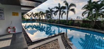 Outdoor pool area with palm trees and city skyline