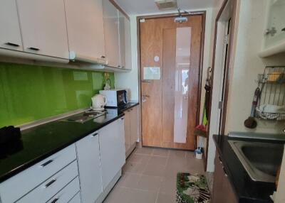 Modern kitchen with green backsplash, white cabinets, and wooden door